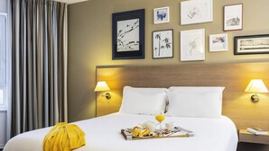 A hotel room with a large bed, two bedside lamps, a tray of breakfast, and wall art. - Mercure Forbach (Forbach)