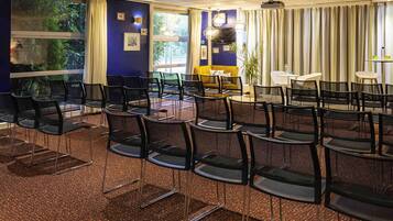 A conference room with black mesh chairs, a yellow sofa, and a TV.