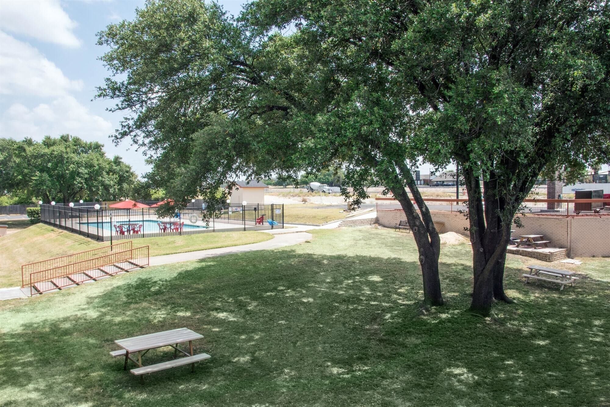 A park with a swimming pool, picnic tables, and a fenced area.
