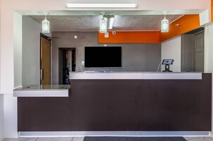 Una recepción con un televisor de pantalla plana, una cámara de seguridad y una pantalla digital.