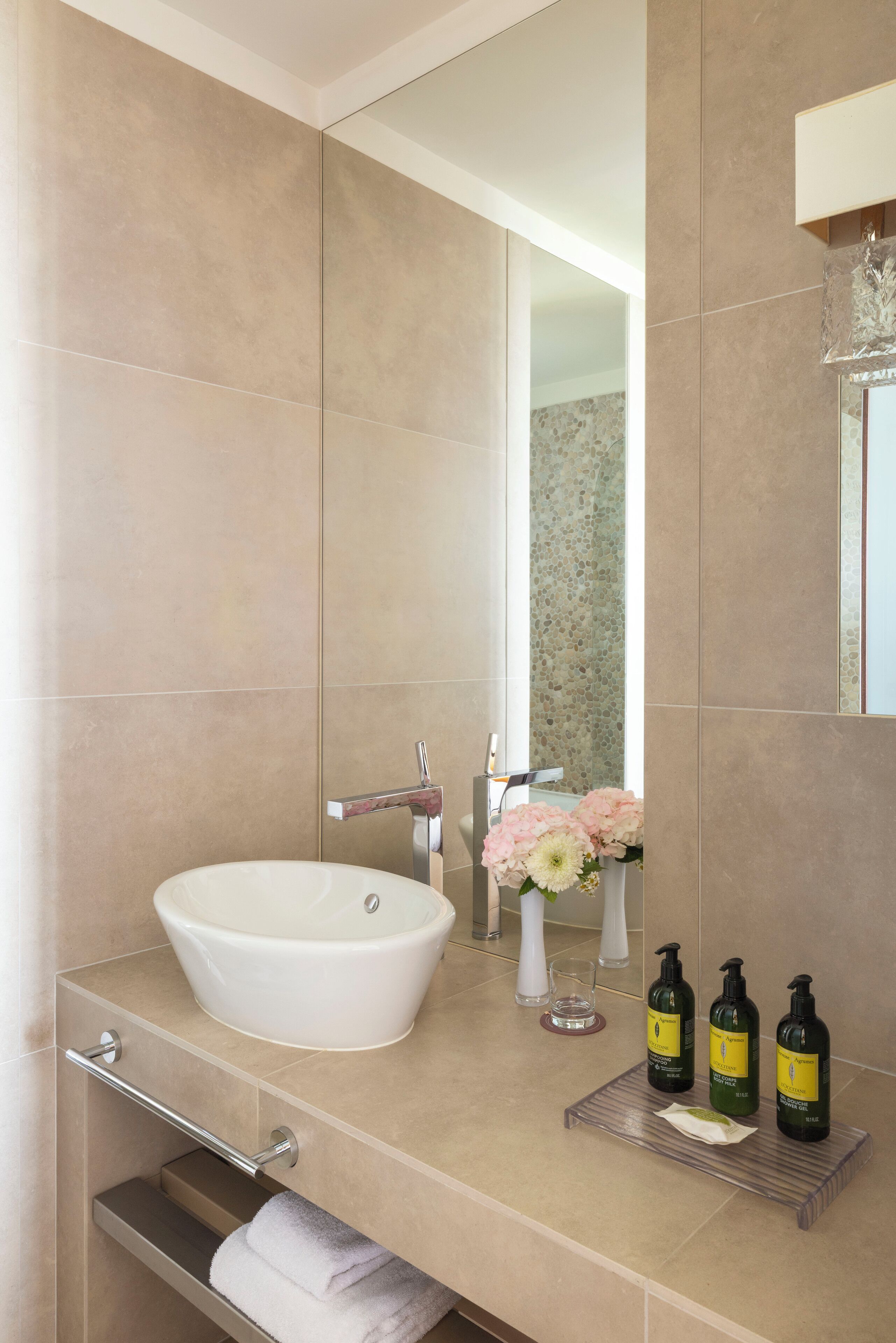 A modern bathroom with a large sink, mirror, and toiletries.