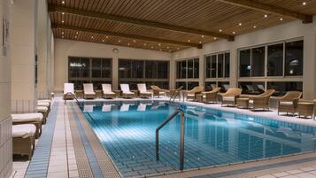 A swimming pool with lounge chairs and a tiled floor.