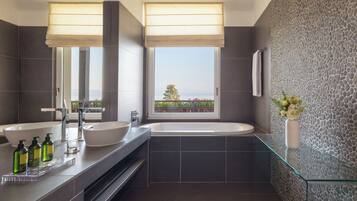 Un baño moderno con una bañera grande, dos lavamanos y una cabina de ducha de vidrio.