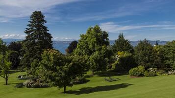 Un campo de golf bien cuidado con vegetación exuberante, cielo despejado y una vista distante de un horizonte urbano.