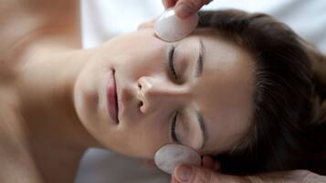 A person receiving a facial treatment with a stone on their forehead.