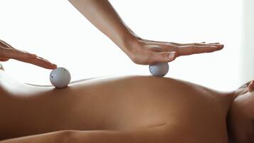 A massage with two golf balls on a person's back.