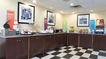 A breakfast bar with a checkered floor, wooden cabinets, and various breakfast items.