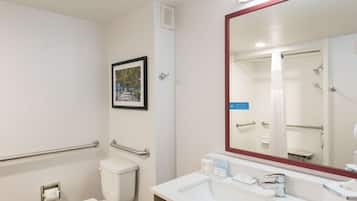 Un baño con inodoro, lavamanos, espejo y ducha.