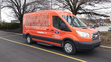 An orange Hampton Inn van parked on a street.