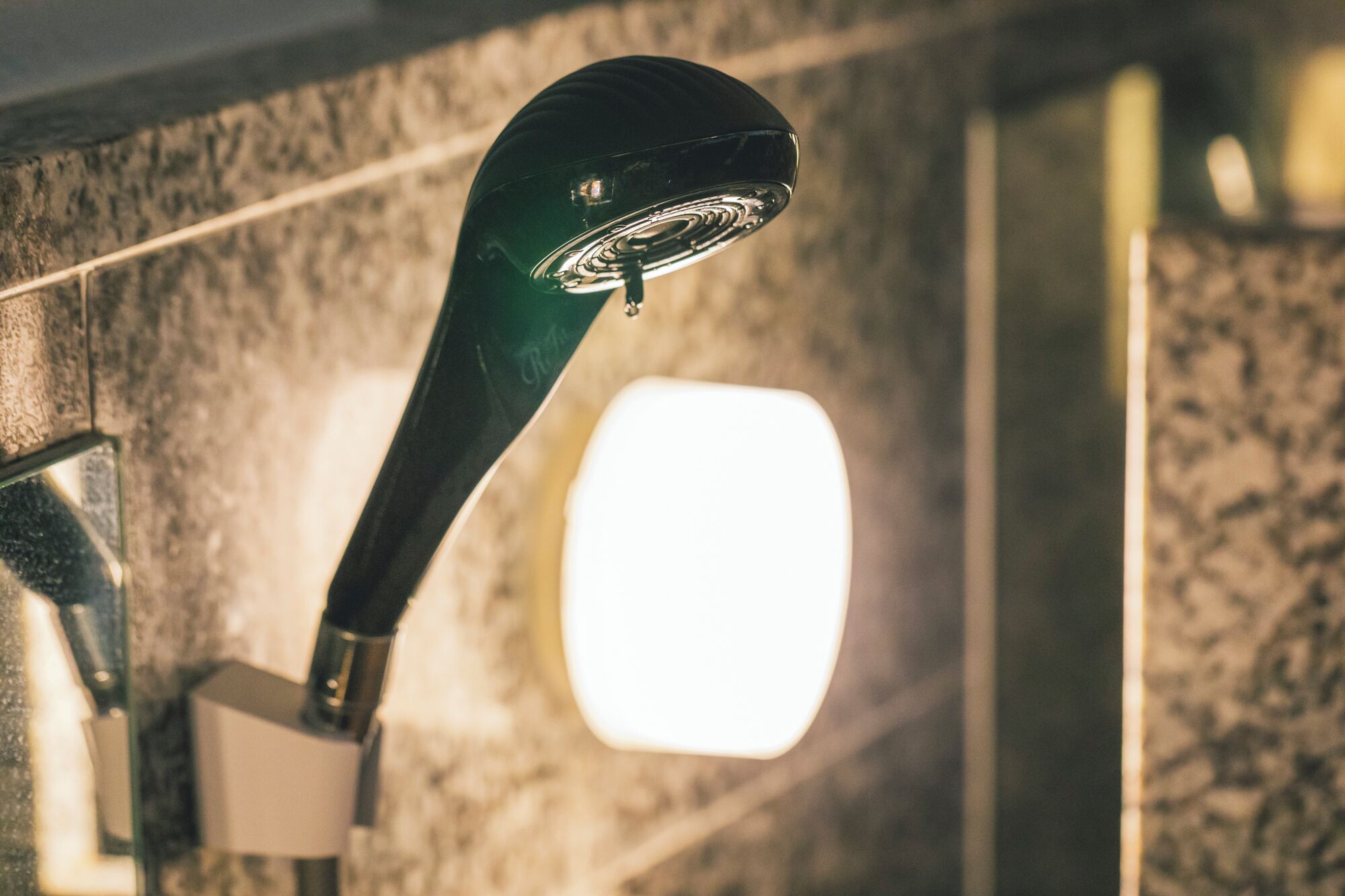A showerhead mounted on a wall with a square mirror.