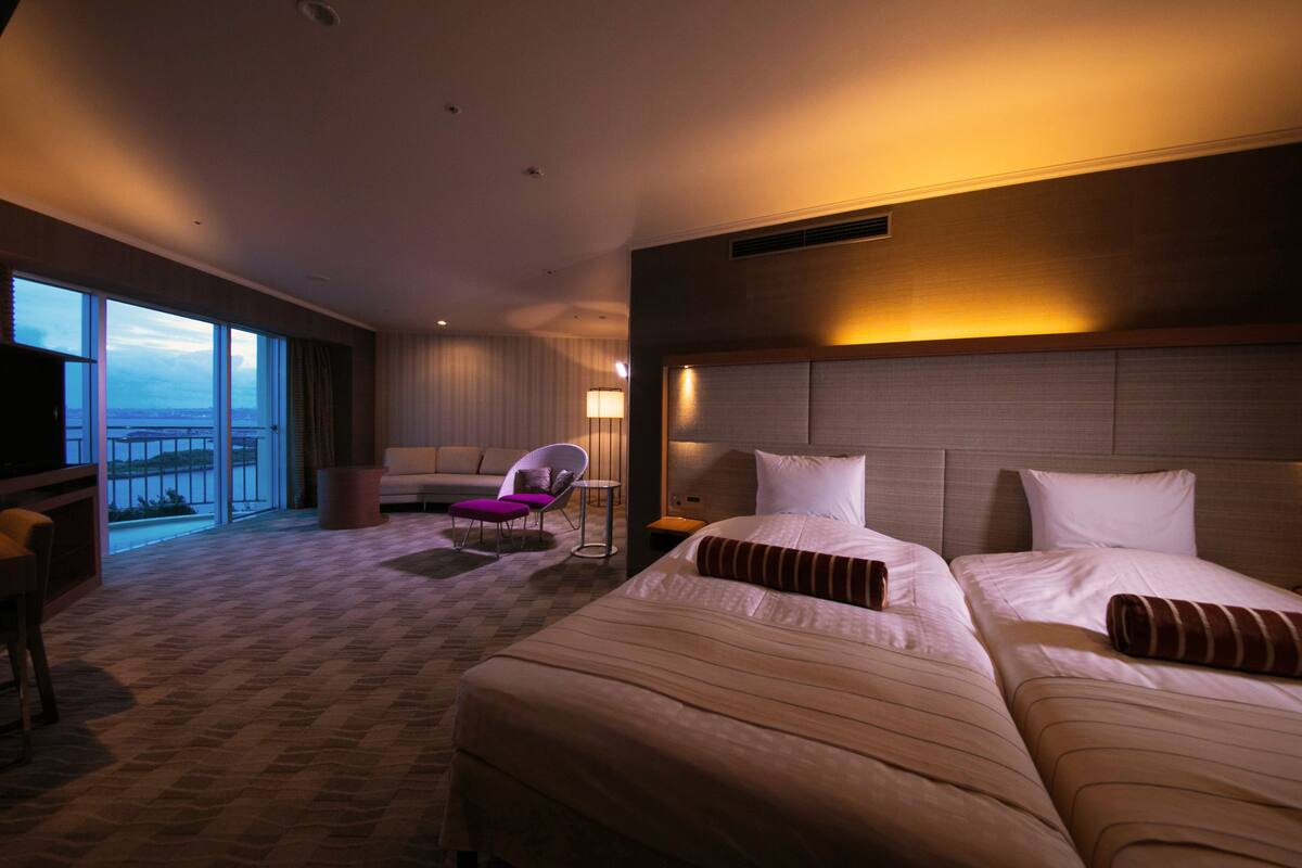 Une chambre d’hôtel avec un grand lit, une chaise, un bureau et une vue sur l’extérieur.
