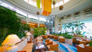 A spacious lobby with multiple seating areas, a central staircase, and large windows allowing natural light. - Laguna Garden Hotel (Ginowan)