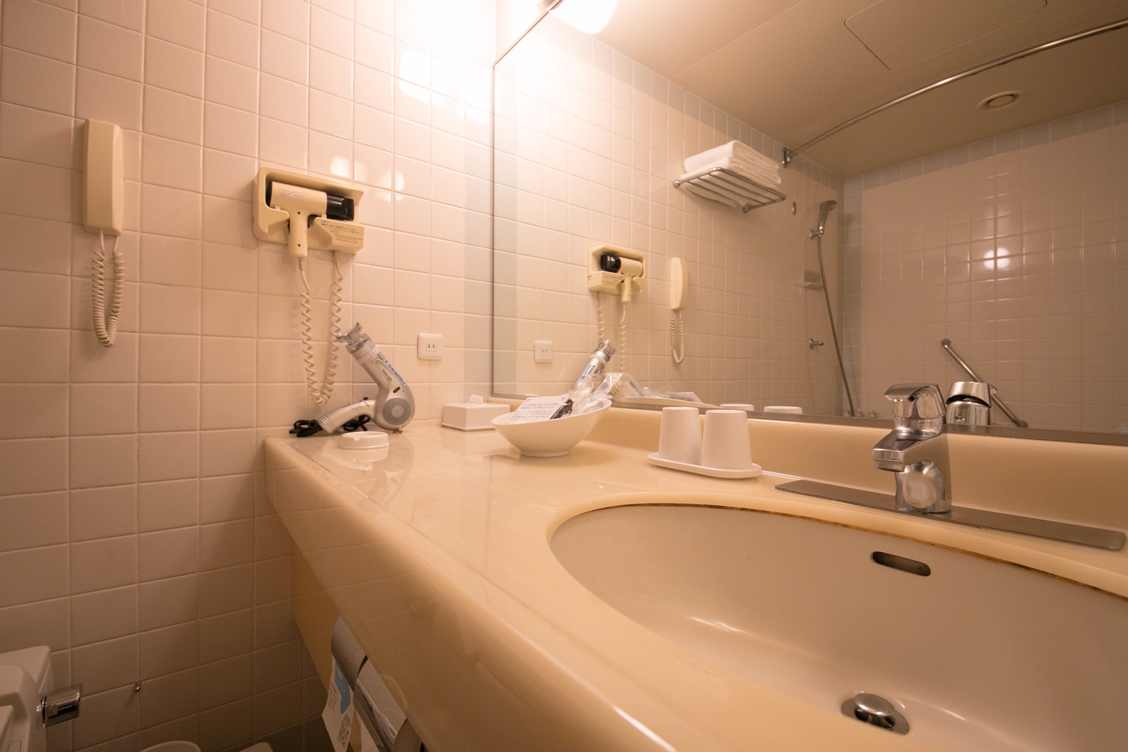 A bathroom with a sink, mirror, and two hair dryers mounted on the wall.