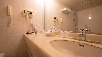 A bathroom with a sink, mirror, and two hair dryers mounted on the wall.