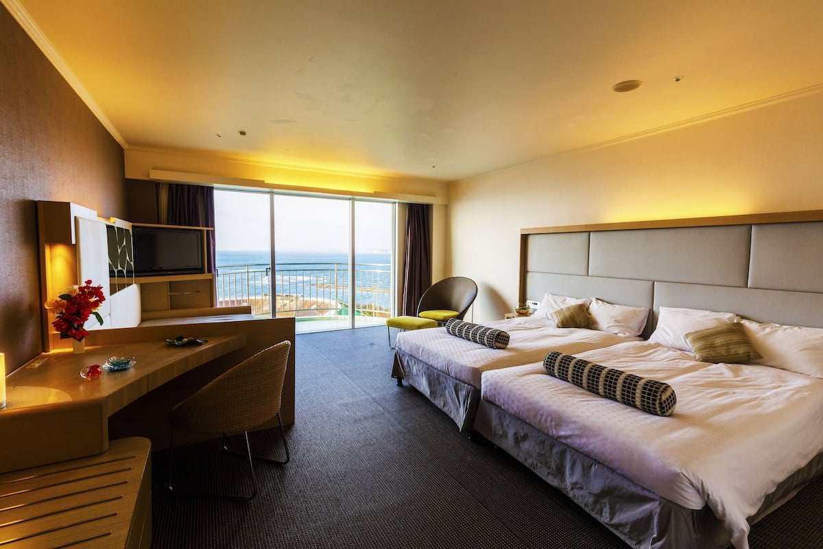 Une chambre d’hôtel avec un lit, un bureau, une chaise et un téléviseur.