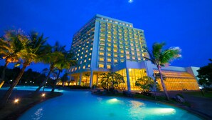 A high-rise hotel with a pool and palm trees. - Laguna Garden Hotel (Ginowan)