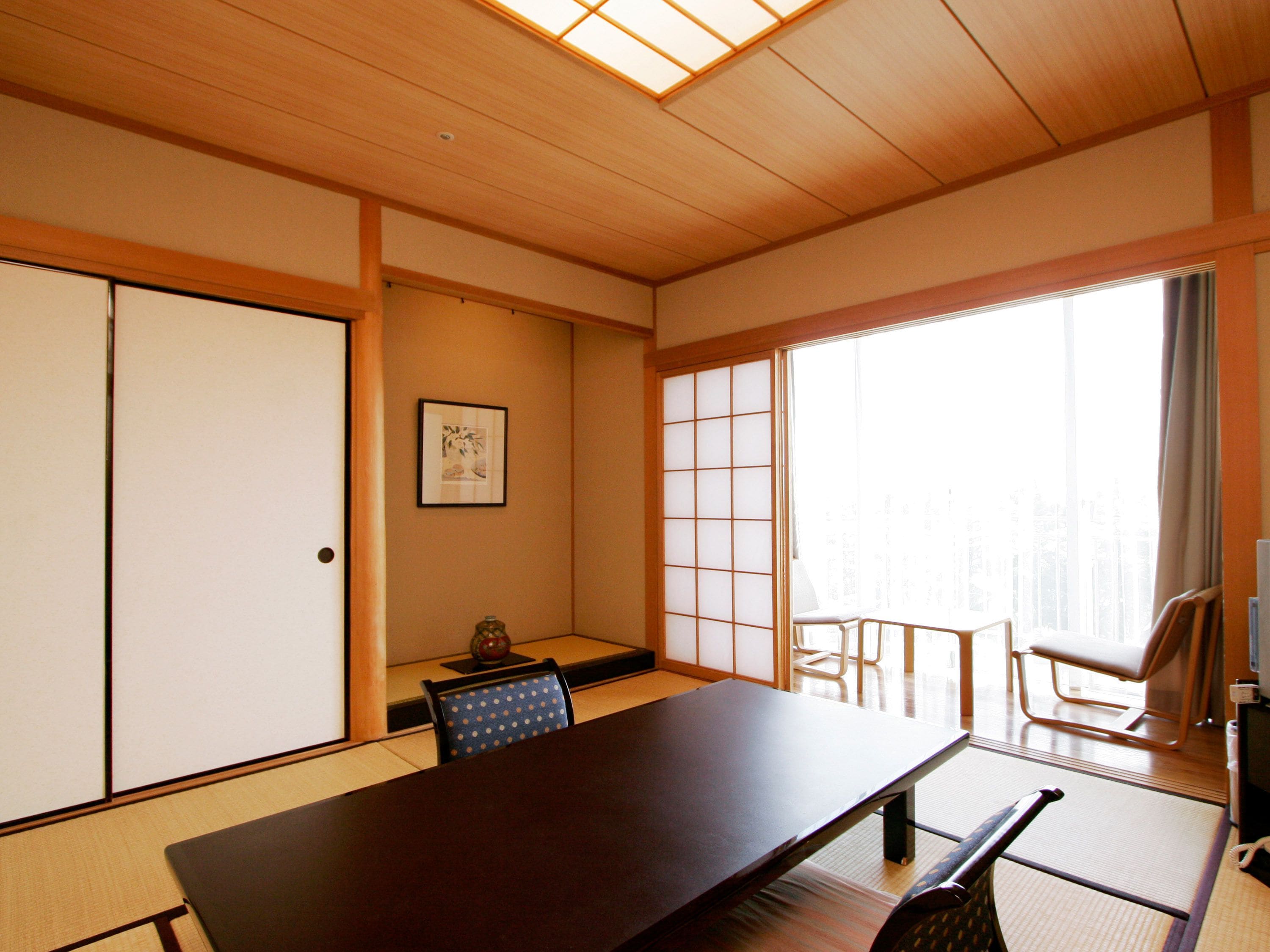 Ein traditioneller japanischer Raum mit Tatami-Böden, einem niedrigen Tisch und verschiebbaren Türen.
