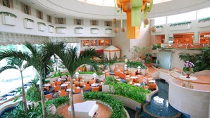 A spacious atrium with a central water feature, multiple seating areas, and a variety of plants. - Laguna Garden Hotel (Ginowan)
