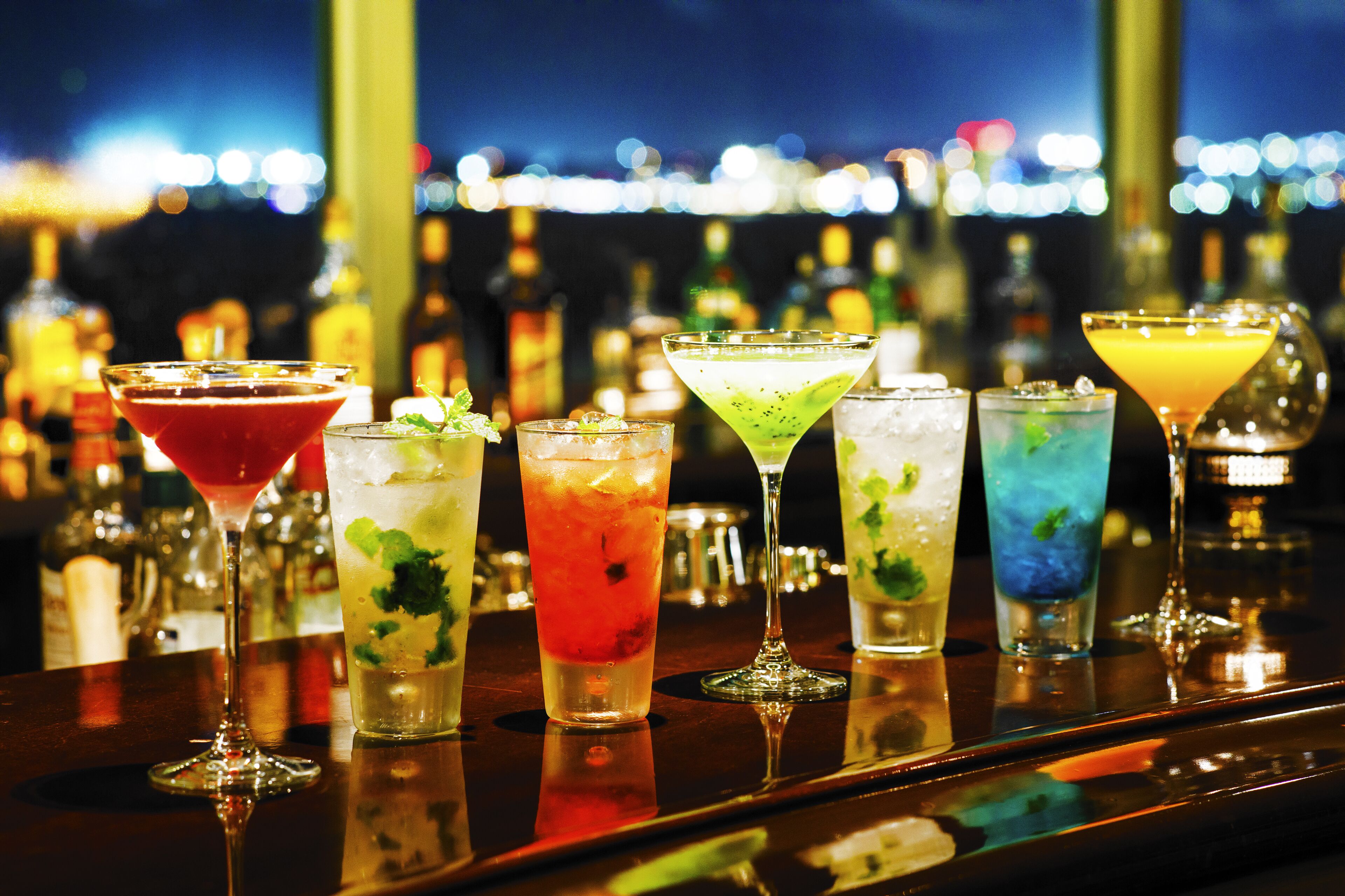 A bar with various colorful cocktails and bottles in the background.