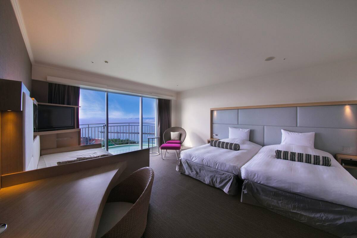 Une chambre d’hôtel avec deux lits, un bureau, une chaise et un téléviseur.