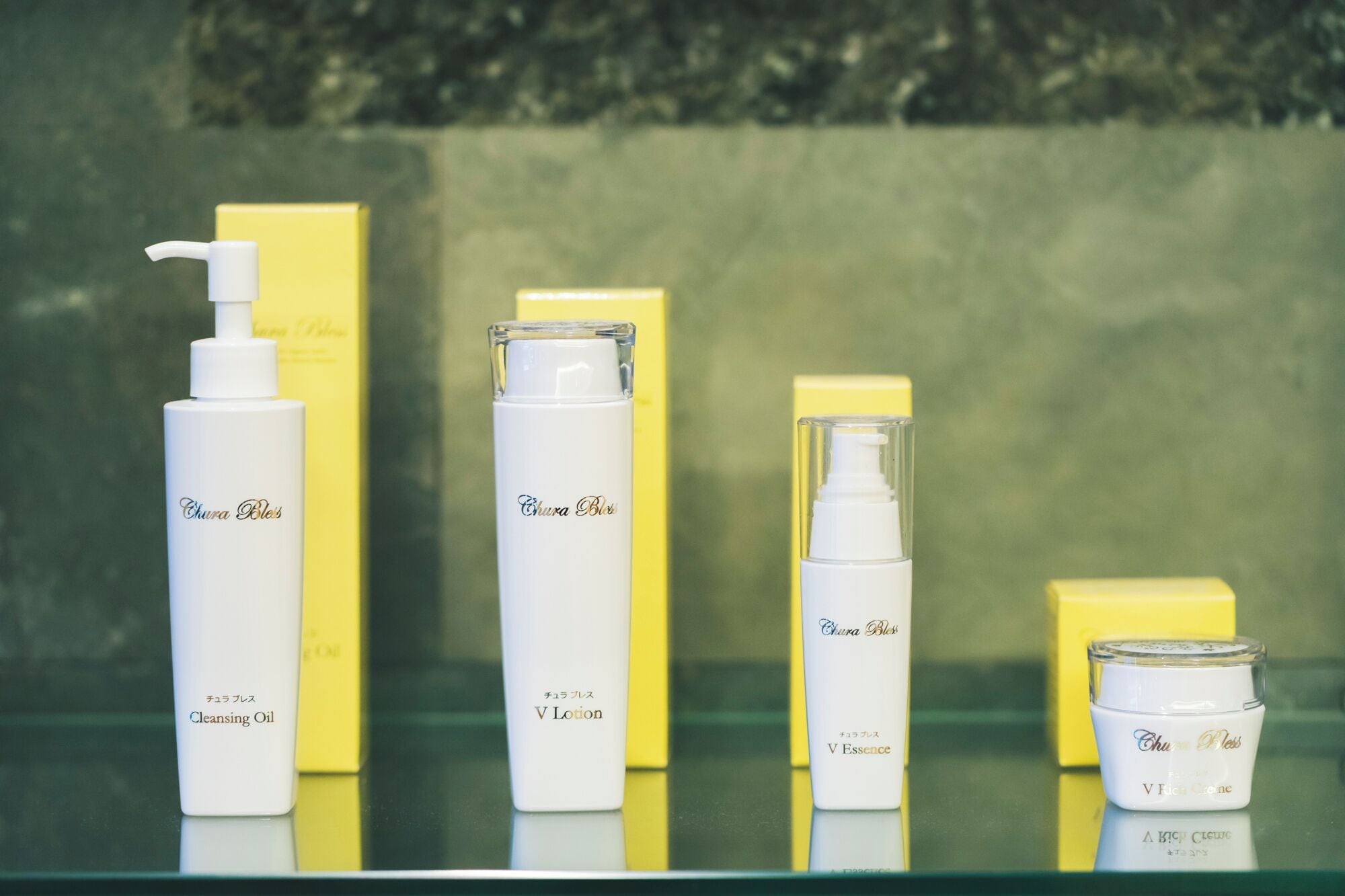 A display of Chura Bles skincare products including a cleansing oil, lotion, essence, and a jar, all in white bottles with yellow boxes.