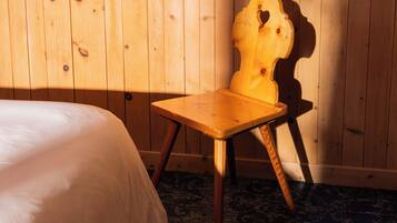 Uma cadeira de madeira com encosto em formato de coração em um quarto com paredes de madeira e carpete estampado.