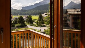Une vue depuis un balcon donnant sur une rivière, avec des montagnes en arrière-plan et des bâtiments au premier plan.