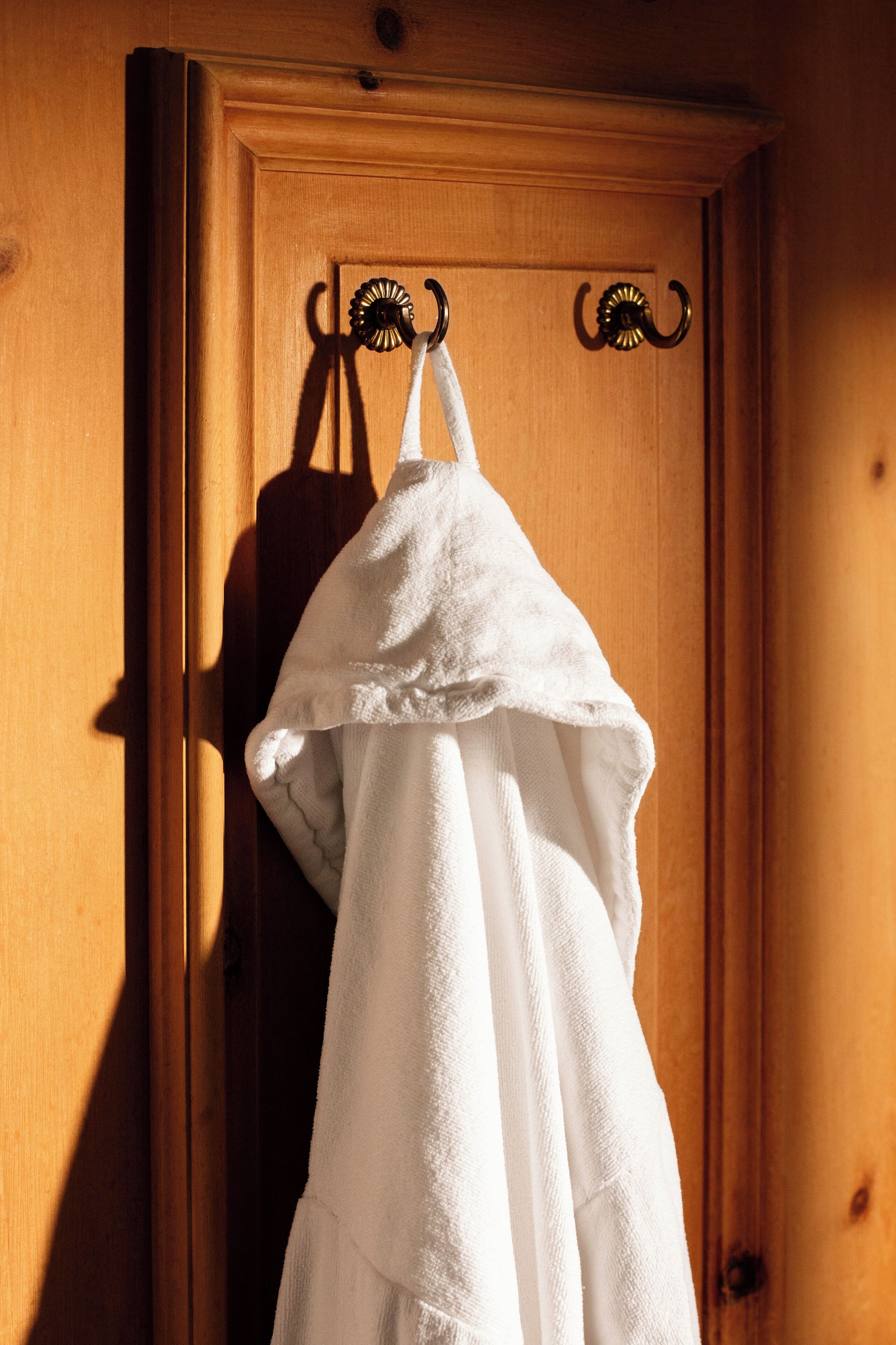 A white towel hanging on a wooden door with a metal towel rack.