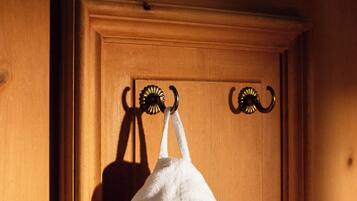 A white towel hanging on a wooden door with a metal towel rack.
