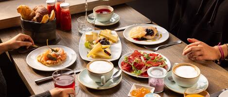 A breakfast setting with various dishes, drinks, and a coffee cup on a wooden table.