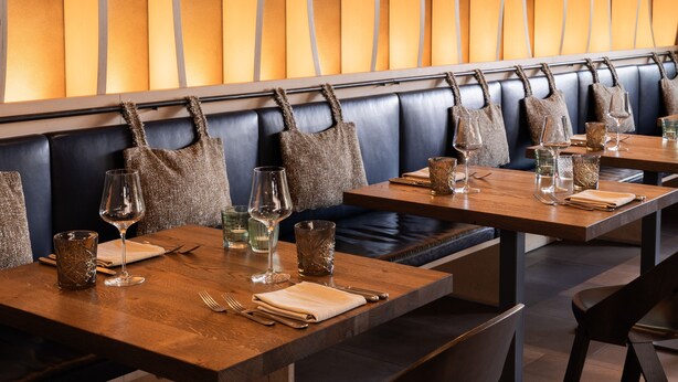 L’intérieur d’un restaurant, avec des banquettes, des tables et un design moderne caractérisé par un mur aux lignes courbes.