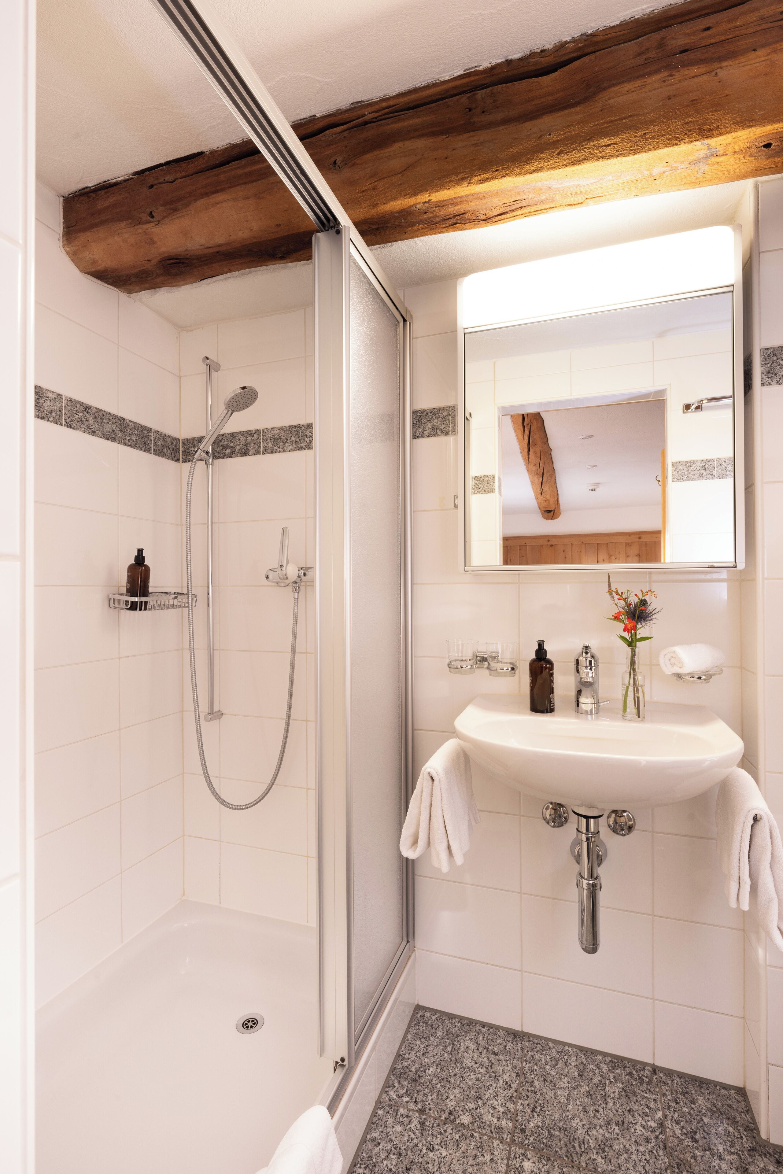 Ein Badezimmer mit Dusche, Waschbecken und Spiegel.