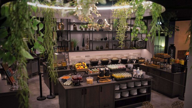 A modern kitchen with a central island, various kitchen appliances, and shelves with decorative items.