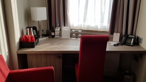 A hotel room with a wooden desk, red chairs, a telephone, a wine bottle, and a menu. - Best Western Plus Hotel Regence (Aachen)