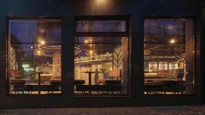 A modern interior with exposed beams, hanging lights, and a seating area with tables and chairs.