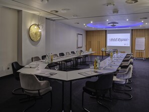 A conference room with a long table, chairs, a projector screen, and a whiteboard. - Best Western Plus Hotel Regence (Aachen)