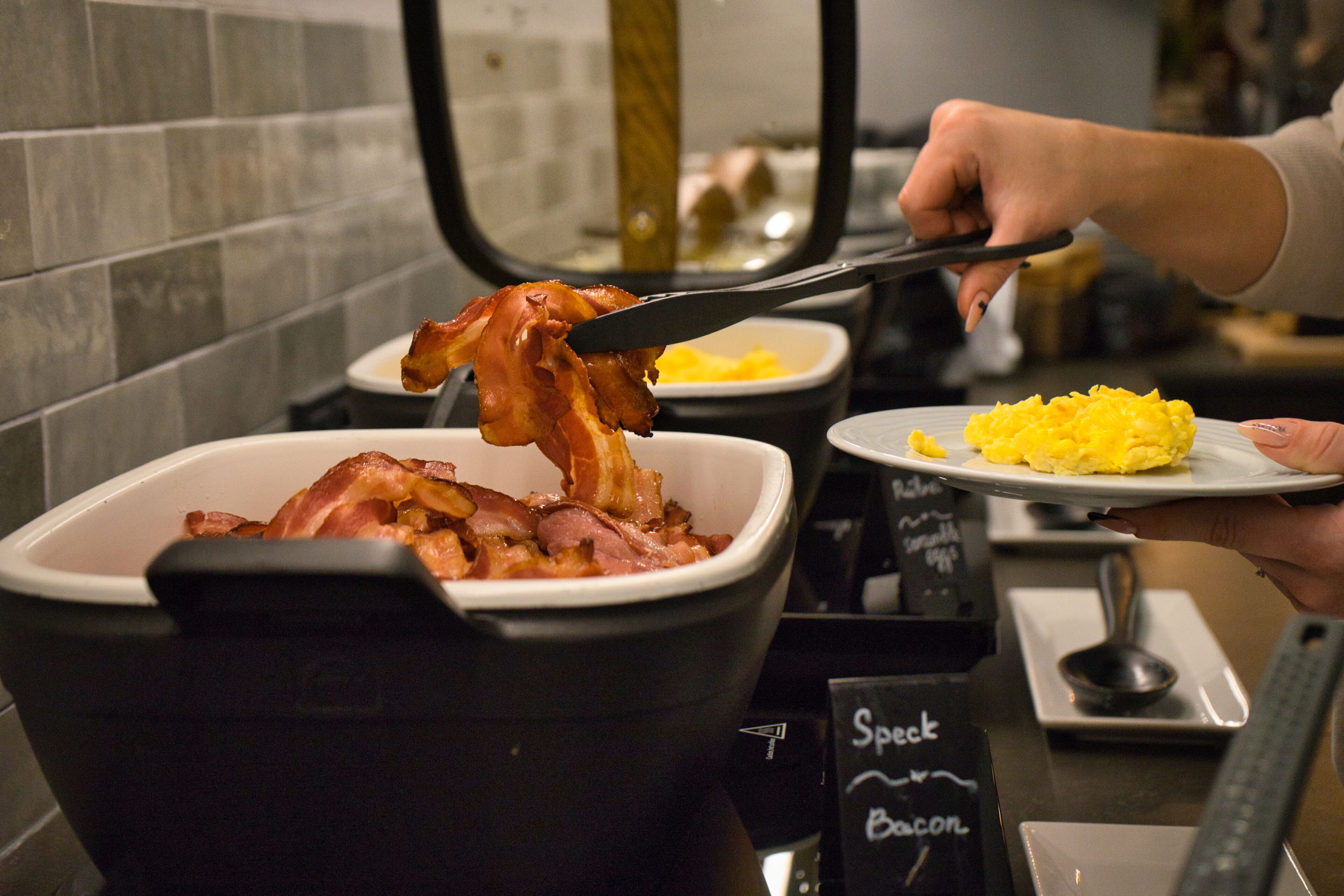 A breakfast buffet with a variety of dishes including bacon and scrambled eggs.