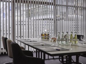 A conference room with a long table, chairs, and a white partition with vertical slats. - Best Western Plus Hotel Regence (Aachen)