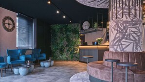 A modern lobby with a reception desk, seating area, and a wall with a vertical garden.