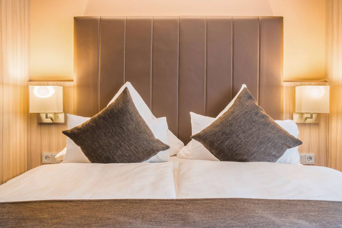 A hotel room with a large bed, two bedside lamps, and a headboard with vertical panels.