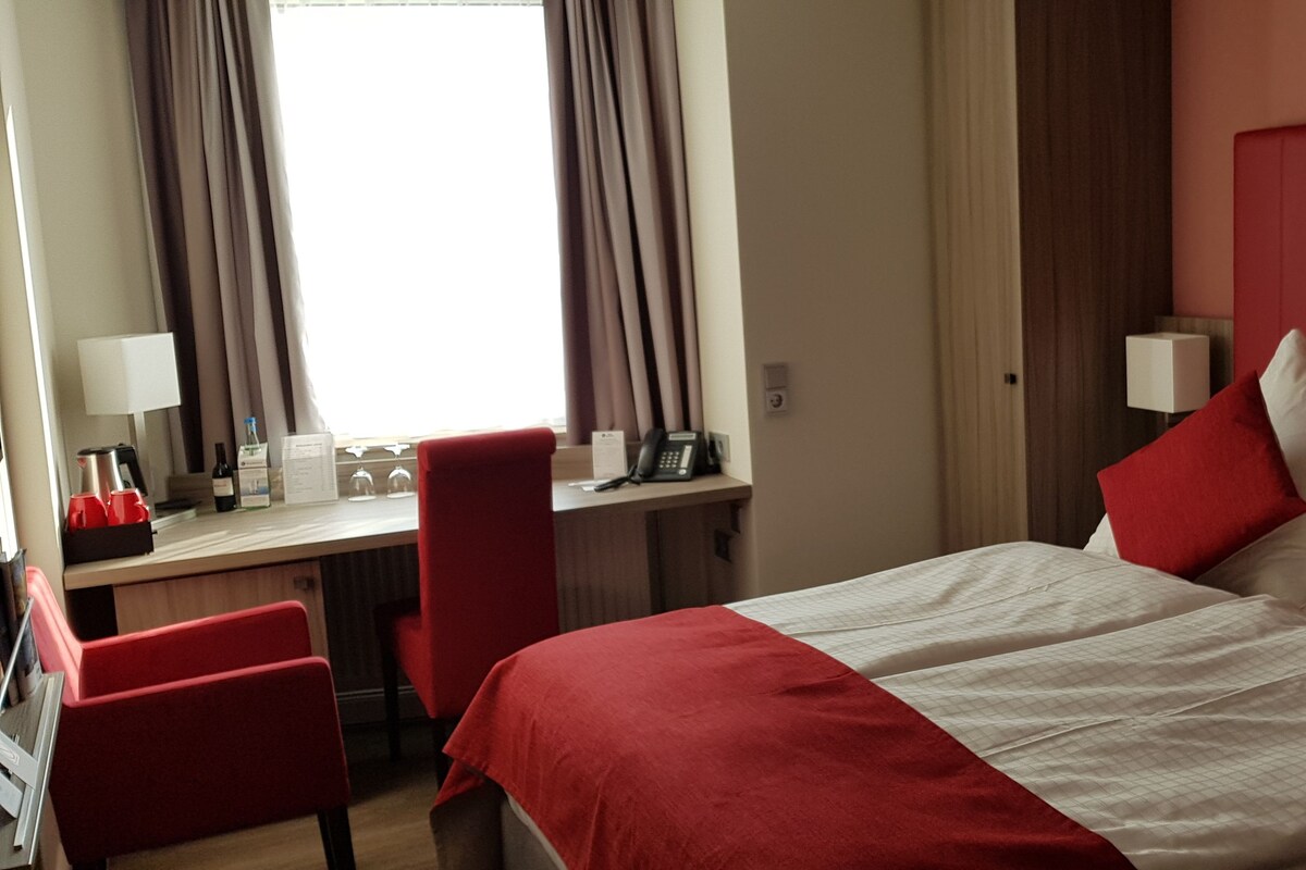 A hotel room with a bed, a desk, and two chairs.