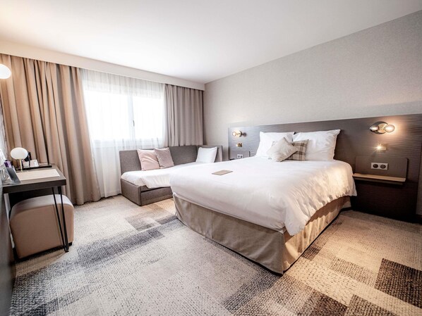 Una habitación de hotel con una cama grande, mesitas de noche, un escritorio y una silla.