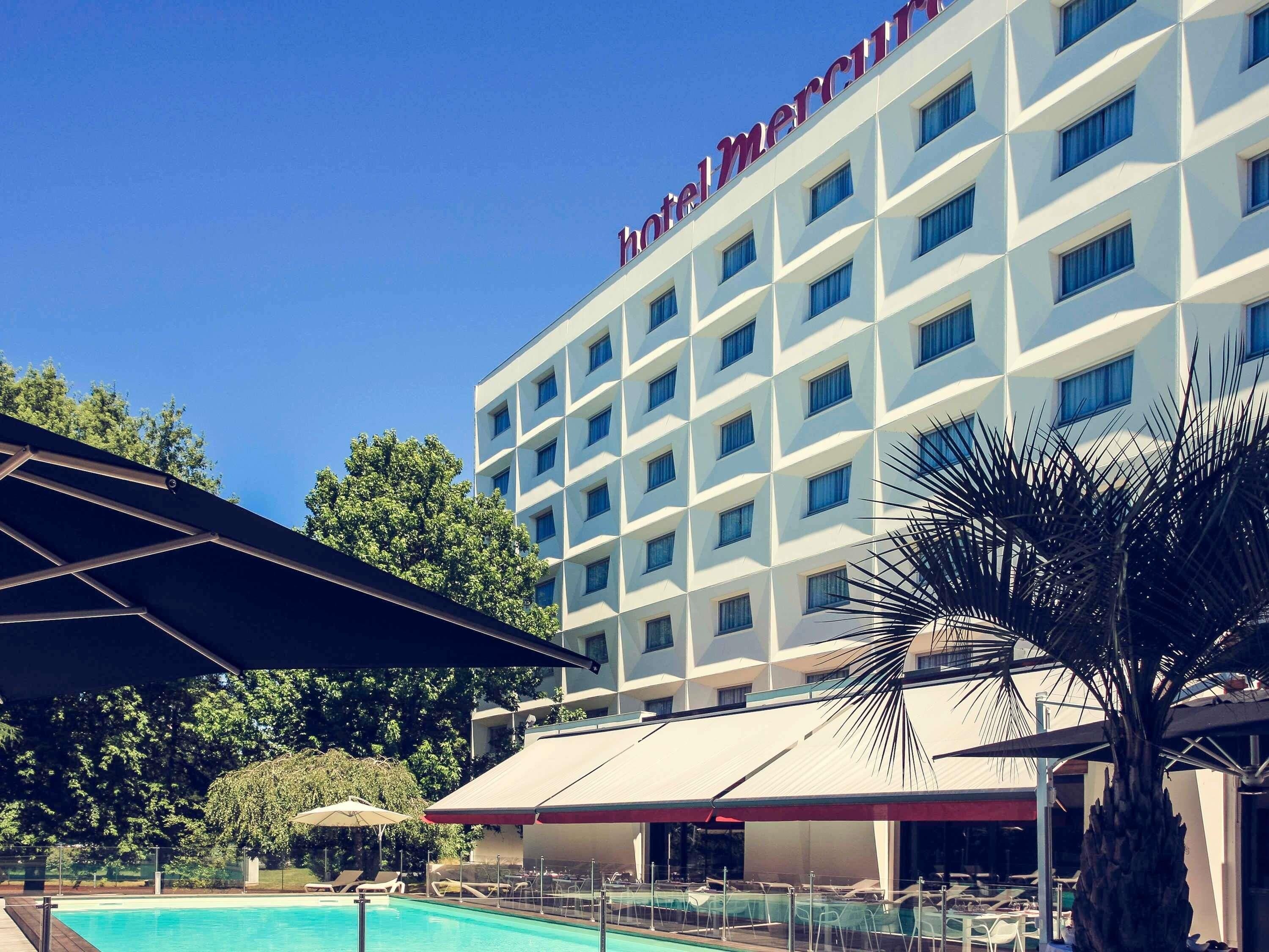 Un hotel con piscina, zona de estar al aire libre y un cielo azul despejado.