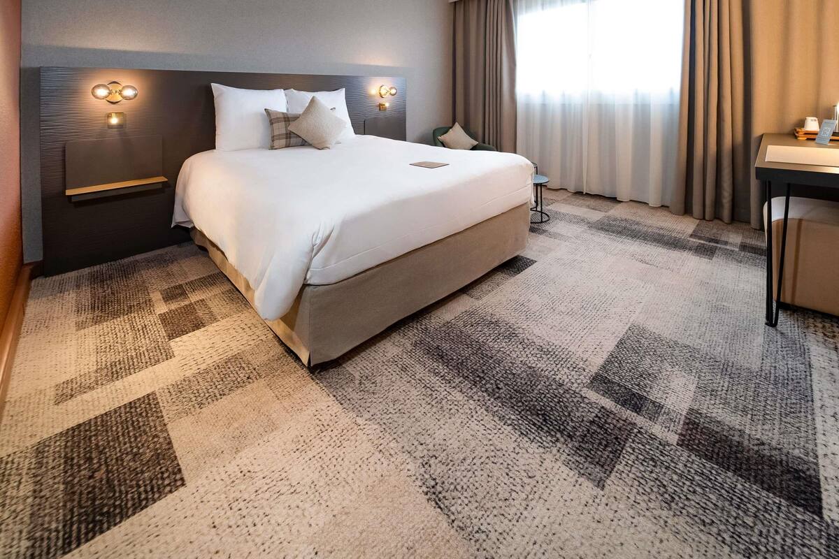 A hotel room with a large bed, a desk, and a chair.