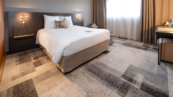A hotel room with a large bed, a desk, and a chair.