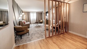 Una habitación de hotel moderna con un separador de madera, un conjunto de sofá, una mesa de centro y una lámpara.