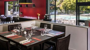 Un comedor con mesas dispuestas para el servicio, una zona de bar con una máquina de café, y vistas a la piscina.