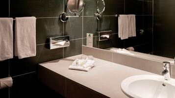 Un baño moderno con un espejo grande, dos toalleros, un lavamanos y un dispensador de pañuelos.