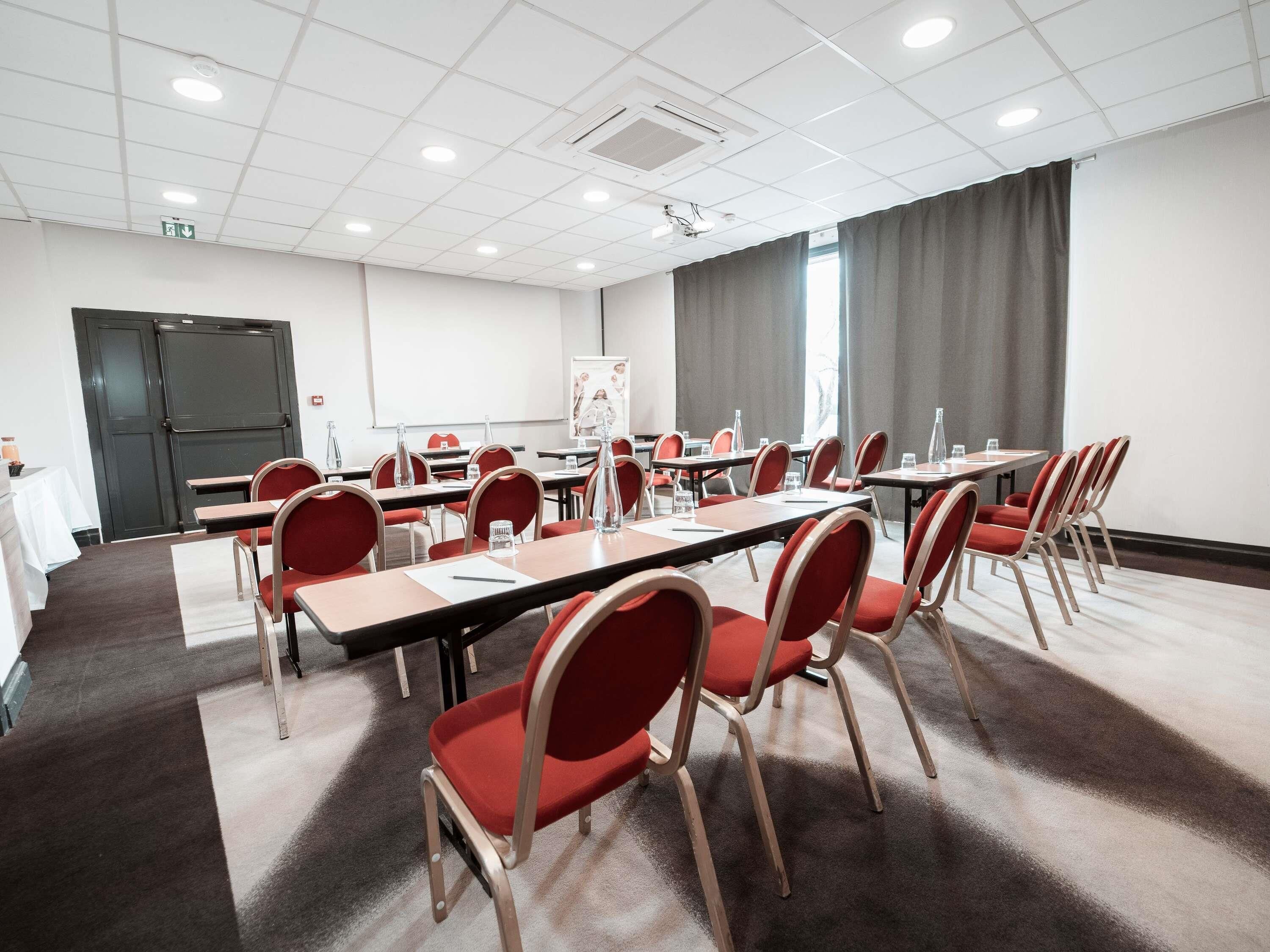 Een vergaderzaal met tafels, stoelen en een whiteboard.