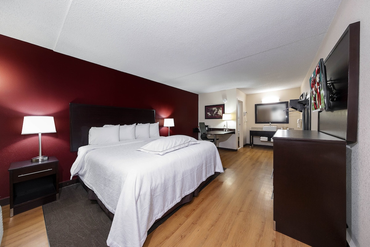 Une chambre d’hôtel comprenant un lit, deux tables de chevet avec lampes, un bureau, une chaise, une télévision et un réfrigérateur.